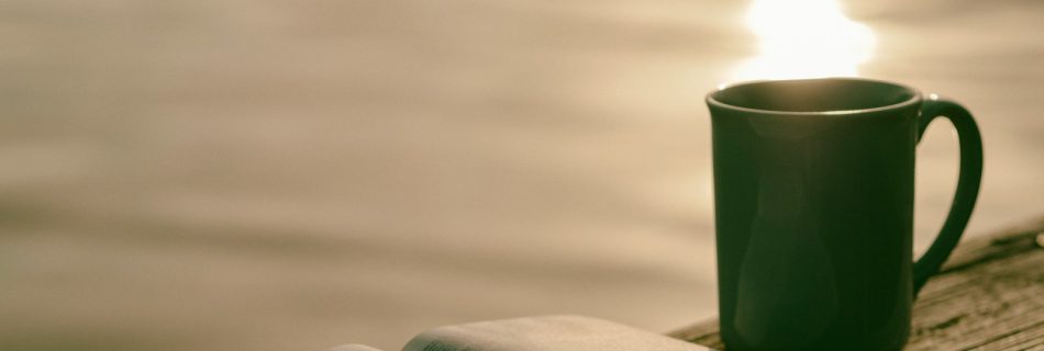 green ceramic mug beside book