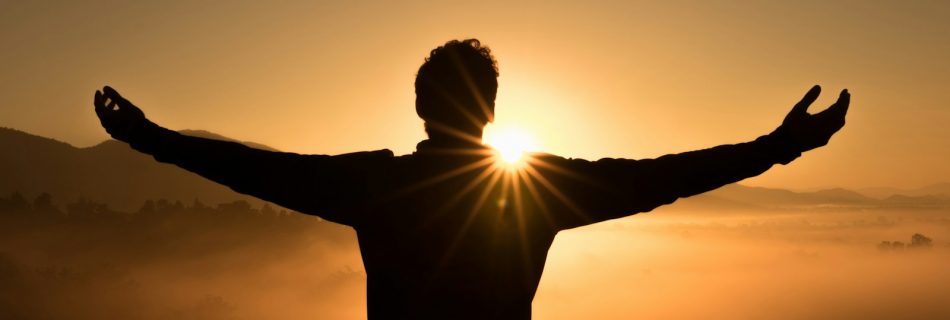 silhouette photo of man on cliff during sunset