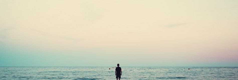 silhouette of person standing on sea dock under cloudy sky