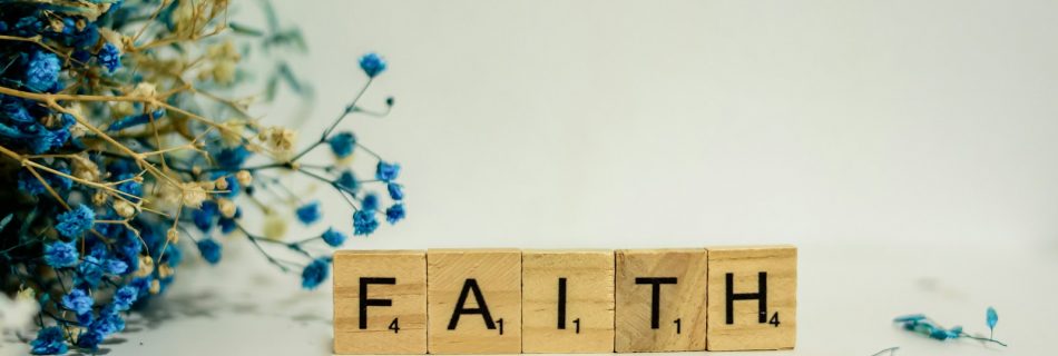 a wooden block that says faith next to blue flowers