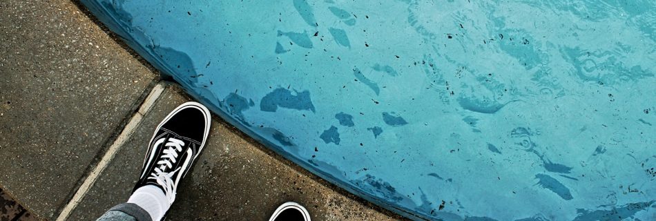 person wearing black and white sneakers standing on blue and brown concrete floor